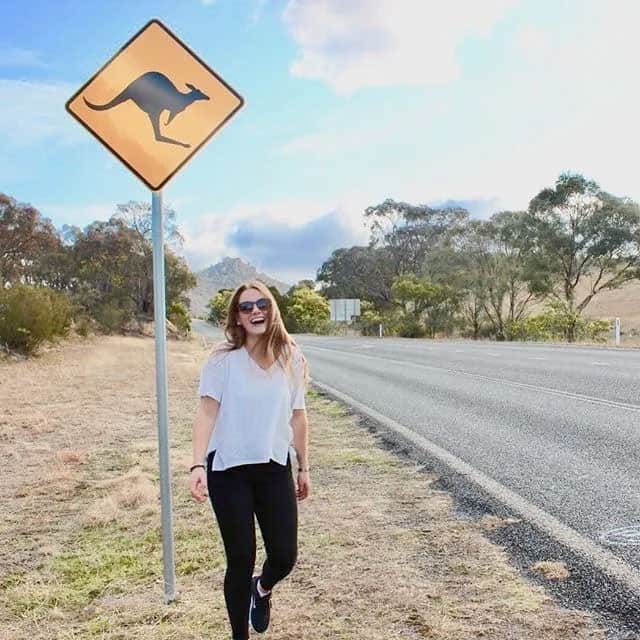 Young woman standing by a kangaroo crossing sign.